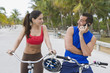 © Kikor/Blend Images - Hispanic man on bicycle talking on cell phone while girlfriend waits
