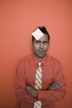 Mixed Race Businessman With Sticky Note On Forehead