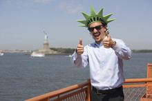 Mixed Race Businessman On Ferry Wearing Statue Of Liberty Hat