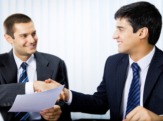 Businesspeople, or businessman and client, with document