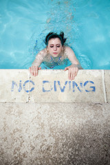 Wall Mural - beautiful brunette woman in a bikini surfacing at poolside