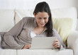 © JGI/Tom Grill/Blend Images - Hispanic woman using laptop on sofa