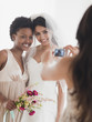 © JGI/Jamie Grill/Blend Images - Woman taking picture of bride and bridesmaid