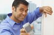 © Rolf Bruderer/Blend Images - Hispanic businessman text messaging on cell phone