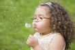 © REB Images/Blend Images - Hispanic girl blowing dandelion