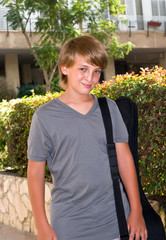 Portrait of a boy with a guitar in its case.