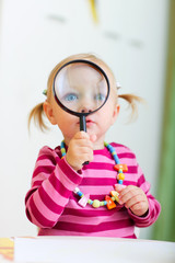 Canvas Print - Toddler girl playing with magnifier