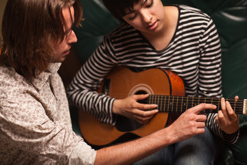 young musician teaches female student to play the guitar