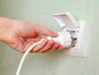 Sticking an electric plug in socket on the wall
