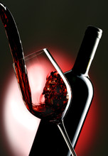 Pouring Red Vine Into Glass With Bottle In The Background.