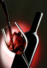 Pouring Red Vine Into Glass With Bottle In The Background.