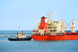 Fototapeta Desenie - Tug boat helps to maneuver the ship