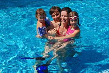 Happy family of four in swimming pool