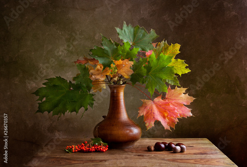 jesienna-martwa-natura-kolorowe-liscie-klonow-w-wazonie-i-jarzebina-z-kasztanami-na-stole