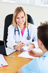 Beautiful doctor giving a prescription to her male patient