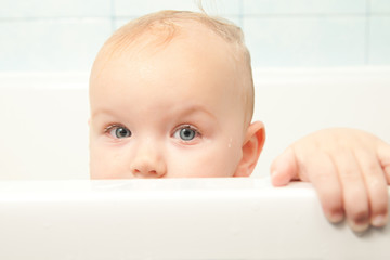 Wall Mural - cute cheerful baby looking from bath hideout