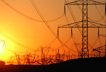 transmission tower against the sun during sunset