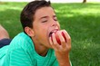 © lunamarina - boy teenager eating red apple on garden grass