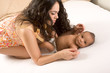 Latina mother playing with her baby boy son on bed