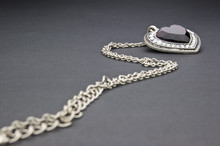 Silver Necklace With Heart-shaped Pendant On A Black Background