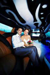 Happy bride and groom in wedding limo