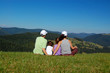© Iuliia Sokolovska - Family sitting on the grass and looking at mountain view