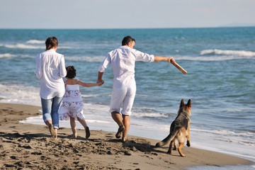 happy family playing with dog on beach