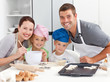 © WavebreakMediaMicro - Portrait of a joyful family cooking littles cakes