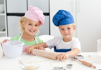 happy brother and sister preparing a dough standing in the kitch