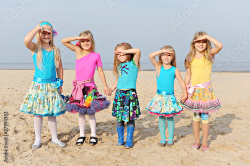 Five little girls standing on the beach and looking at the sun ...