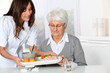 © goodluz - Beautiful nurse bringing meal tray to old woman at nursing home