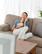 © WavebreakMediaMicro - Cheerful woman watching television and eating pop corn