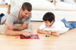 © WavebreakMediaMicro - Handsome man playing checkers with his son lying on the floor