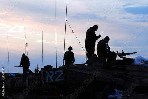 Tela Silhouette of men preparing their tanks and weapons at sunset