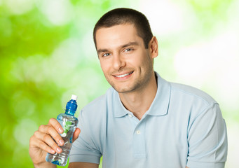 Young happy smiling man with bottle of water, outdoors