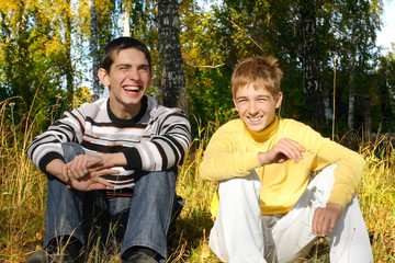 two laughing boys sitting in autumn forest