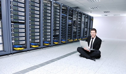 businessman with laptop in network server room