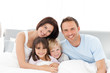 © WavebreakMediaMicro - Portrait of a happy family sitting on the bed