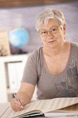 Canvas Print - Senior teacher in school searching in a book