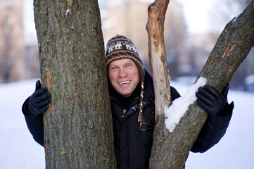 Happy man hugging the tree in winter