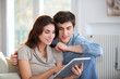 © goodluz - Young couple using electronic tablet at home