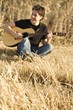 © Vibe Images - Man Playing Guitar In Field