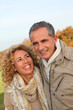 © goodluz - Happy couple walking in country field in autumn
