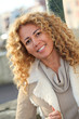 © goodluz - Portrait of smiling blond woman in town