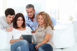 © goodluz - Group of friends sitting in sofa with electronic tab