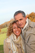 © goodluz - Happy couple walking in country field in autumn