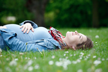 Beautiful Pregnant Woman Relaxing On Grass