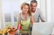 © goodluz - Couple cooking in kitchen with laptop computer