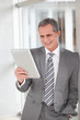 © goodluz - Businessman standing in hall with electronic tab