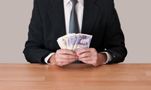 Man In Suit Sitting With Cash - Pounds Sterling
